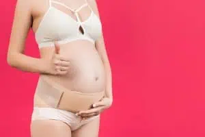 Get Postpartum Relief and Comfort with an Apron Belly Support Band: Here's How it Works! pregnant woman shows thumbs up wearing a belly band